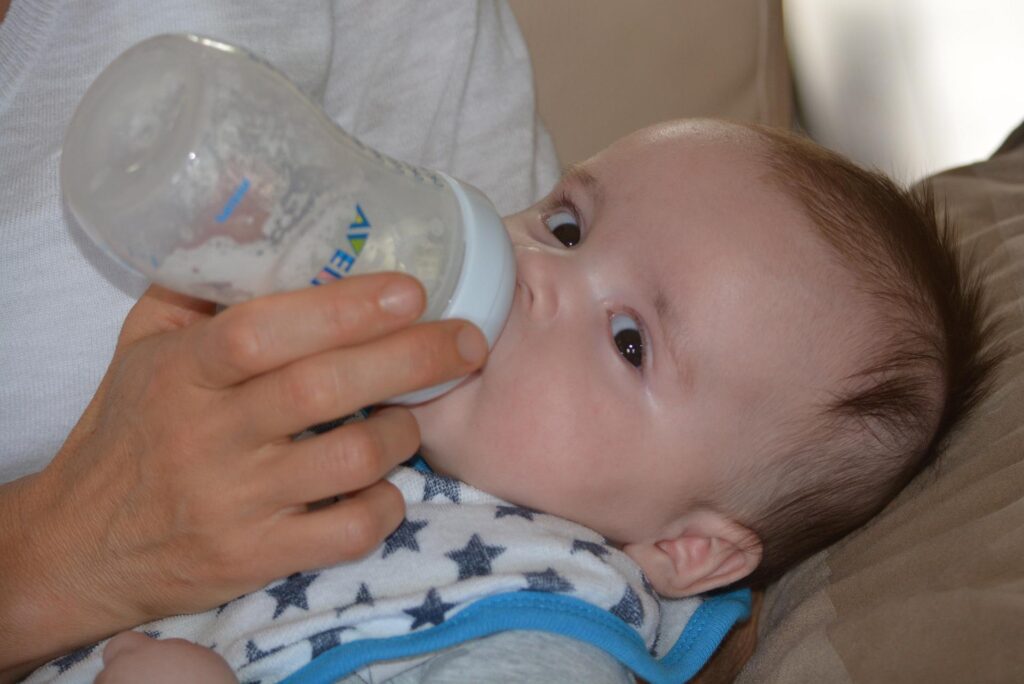 parent feeding baby a bottle of breast mik