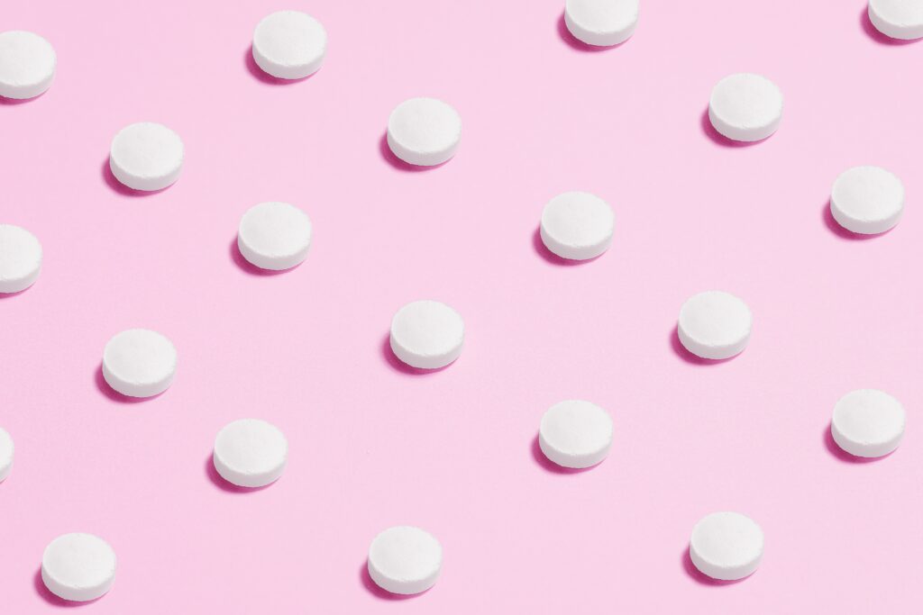 white oval shaped pills on a pink background