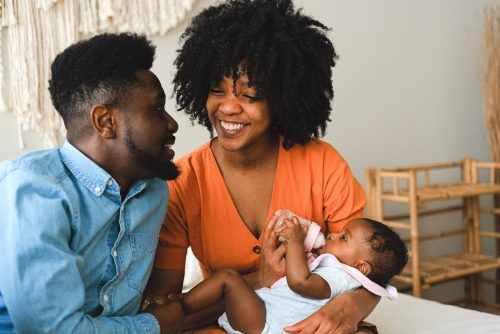 black couple mother and father holding their baby drinking a bottle of breast milk