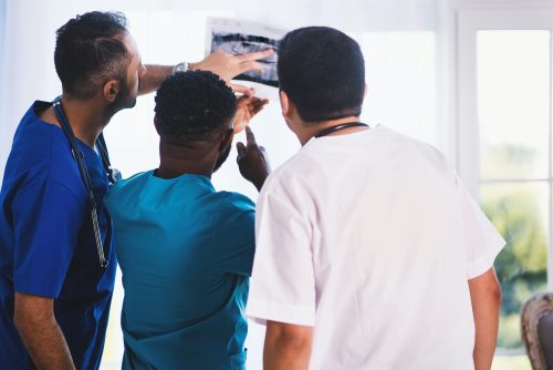 three male doctors looking at medical scans